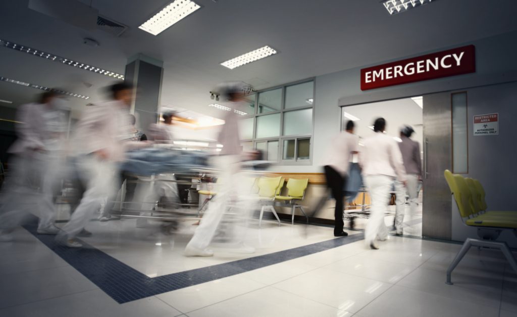 A motion blurred photograph of a patient on stretcher or gurney being pushed at speed through a hospital corridor.New corona virus